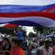 An anti-government protester waves national flags over other protesters gathering in the street near their main encampment after a coup in central Bangkok.